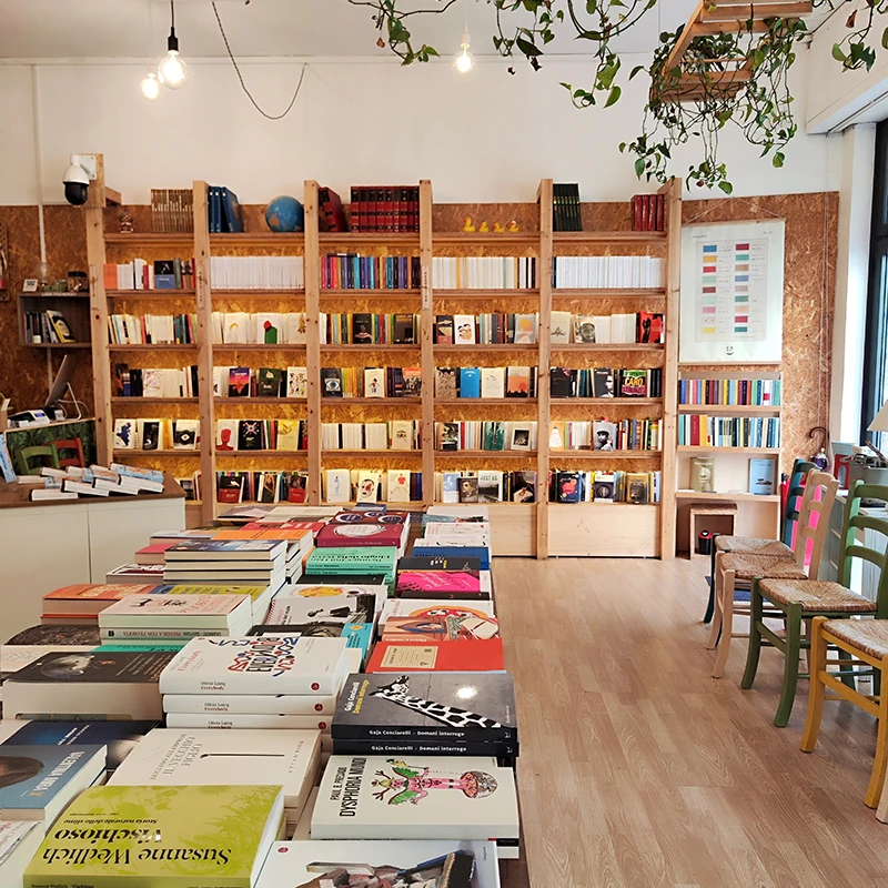 Interno della Libreria Teatro Tlon, con scaffali, tavoli di libri e piante sospese